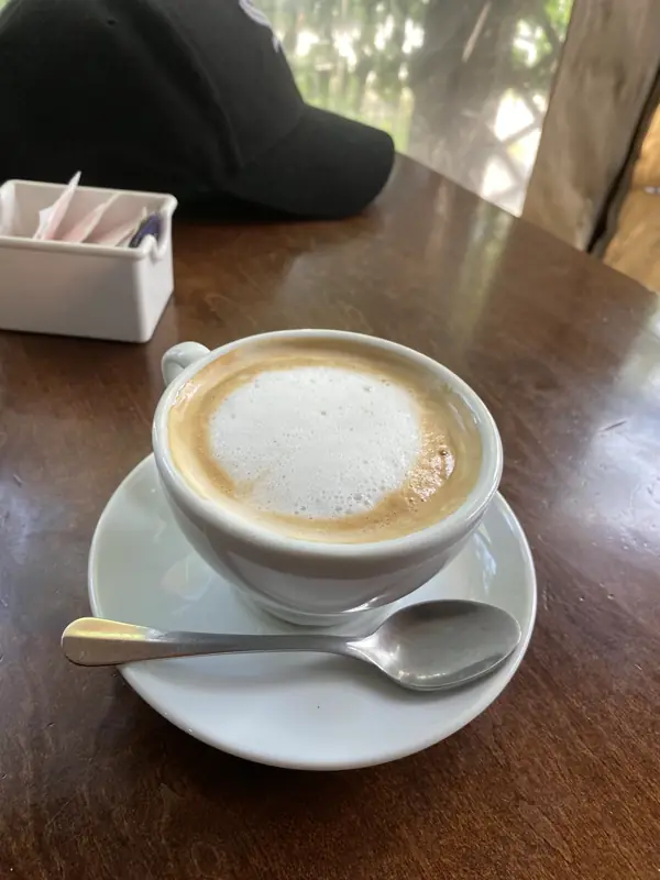 Capuchino en taza blanca sobre una mesa de madera