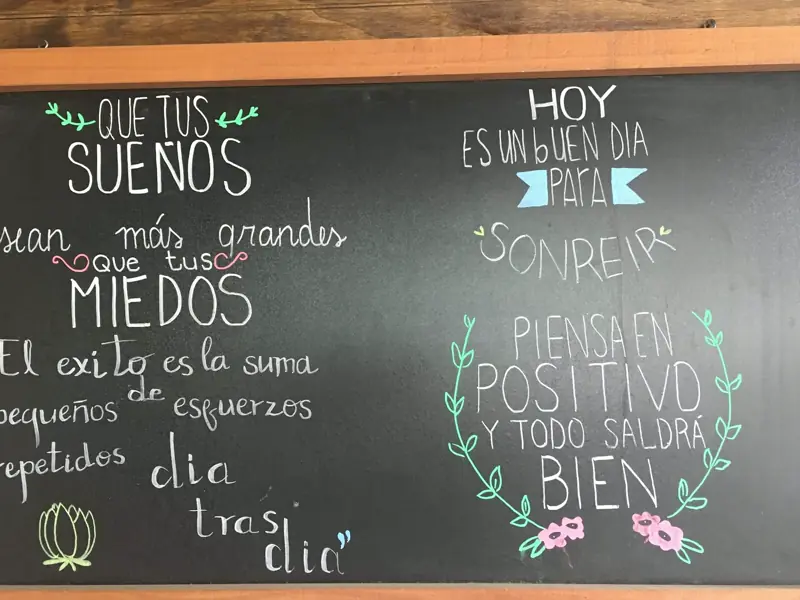 Pizarra del local con frases escritas a mano: «Que tus sueños sean más grandes que tus miedos» y «Hoy es un buen día para sonreír»